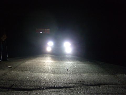 1992 Ford Bronco - Headlights illuminate a dark, wet road at night.
