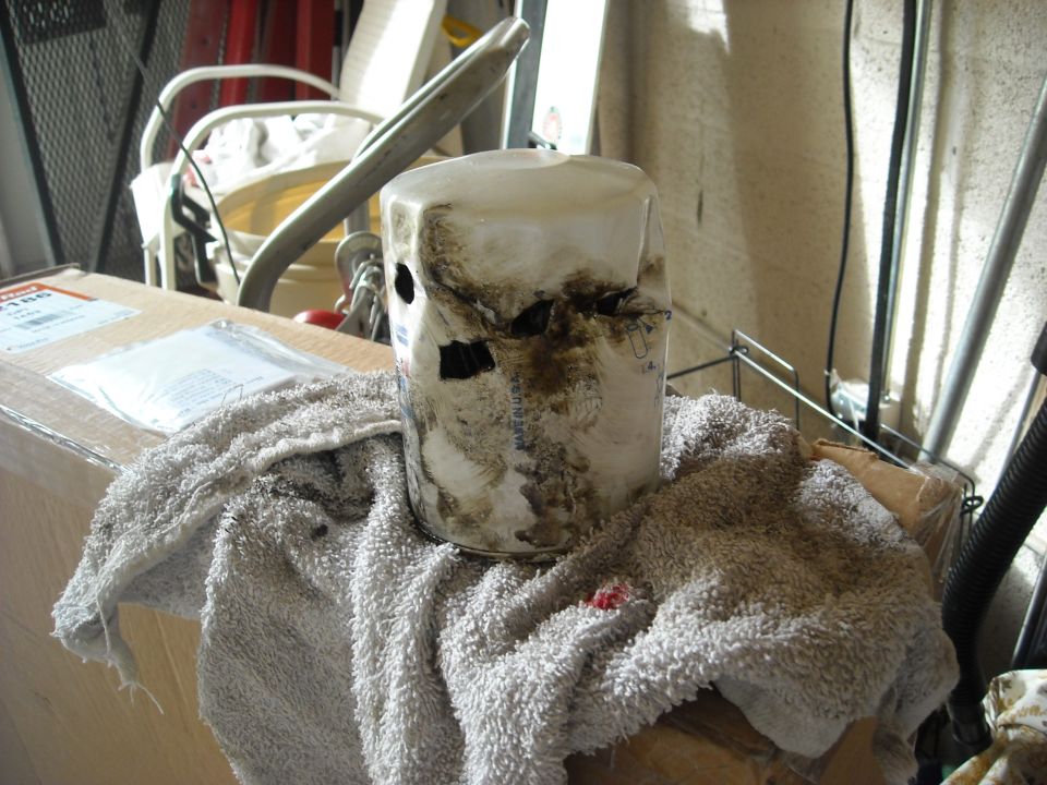 Oil filter covered in grime and oil, resting on a towel next to a cardboard box