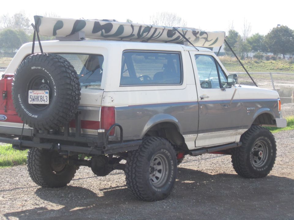 1991 Ford Bronco, two-tone white and grey, with spare tire on rear and kayak on roof rack