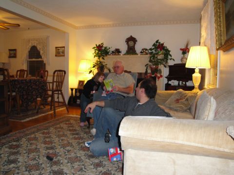 2000 Ford Crown Victoria - A family gathers in a living room, with a fireplace and dining area visible in the background.