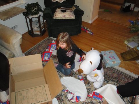 2000 Ford Crown Victoria - A young girl excitedly opens gifts on Christmas morning, surrounded by wrapping paper and a large Snoopy stuffed animal.