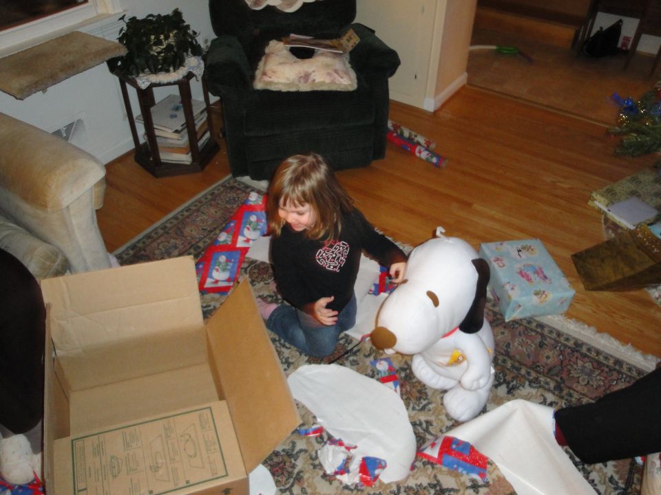 Kid opening presents with a Snoopy plush toy on Christmas morning