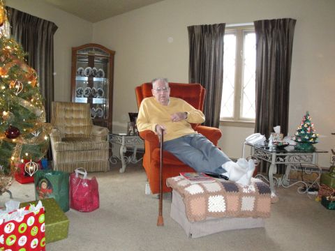 2000 Ford Crown Victoria - Man relaxes in armchair near a Christmas tree, with gifts on the floor.