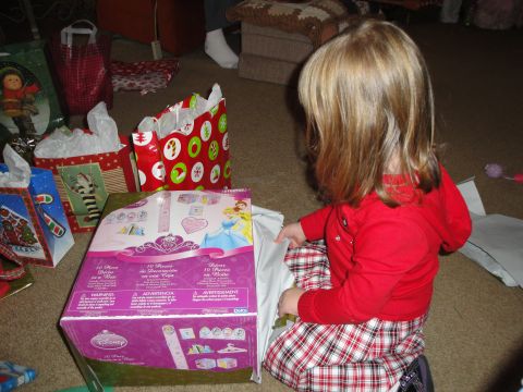 2000 Ford Crown Victoria - A young child unwraps a Disney Princess toy on Christmas morning, with several gift bags in the background.