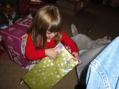 2000 Ford Crown Victoria - A child is excitedly opening a present on the floor, surrounded by wrapping paper and gift boxes.