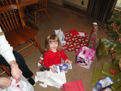 2000 Ford Crown Victoria - A child smiles while opening a present on Christmas morning, with many gifts piled around.