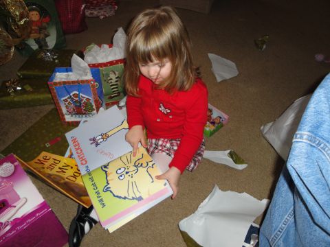 2000 Ford Crown Victoria - A young child sits on the floor surrounded by Christmas presents, engrossed in opening books.