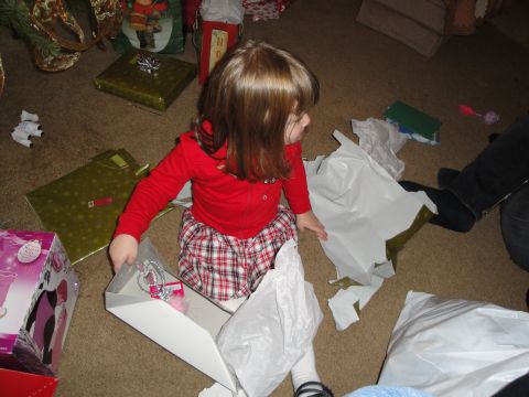 2000 Ford Crown Victoria - A child unwraps presents on the floor, with a Christmas tree and gifts visible in the background.
