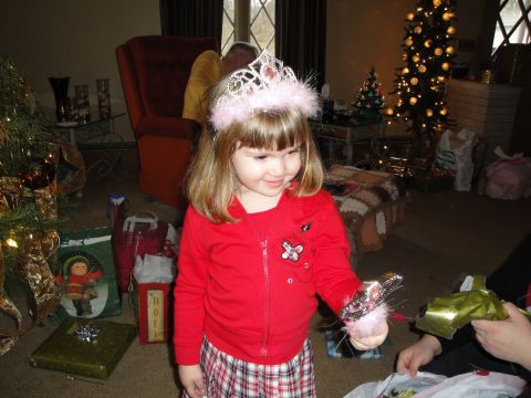 2000 Ford Crown Victoria - A young girl dressed for a holiday celebration opens a gift while wearing a tiara.