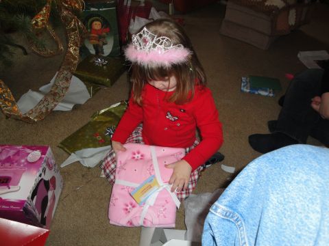 2000 Ford Crown Victoria - A child unwraps a gift on Christmas morning, surrounded by holiday decorations and other presents.