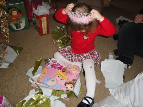 2000 Ford Crown Victoria - A young child plays with a tiara amidst torn wrapping paper and gifts.