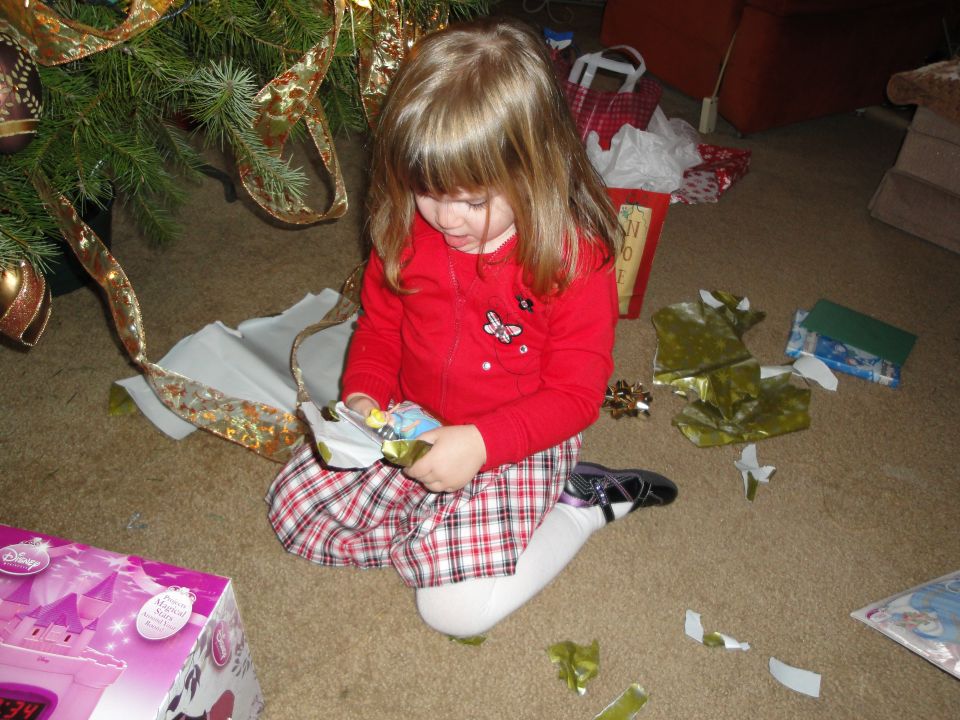Child opening Christmas presents near a tree