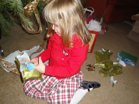 2000 Ford Crown Victoria - A child unwraps a gift near a Christmas tree with wrapping paper scattered around.