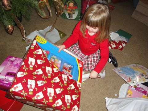 2000 Ford Crown Victoria - A child excitedly opens a Christmas present, surrounded by other gifts and holiday decorations.