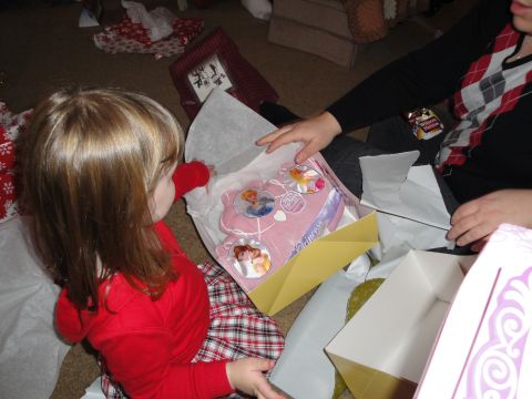 2000 Ford Crown Victoria - A child excitedly opens a pink toy Disney princesses, surrounded by gift wrap.