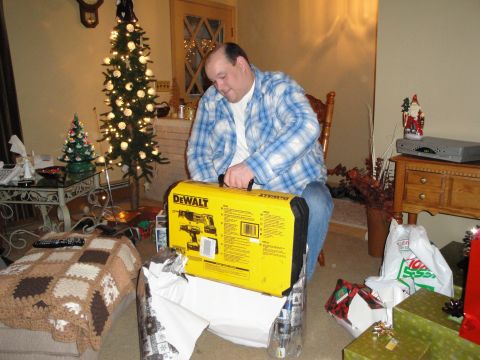 2000 Ford Crown Victoria - Man unwraps a DeWalt drill set on Christmas morning, surrounded by gifts and holiday decorations.