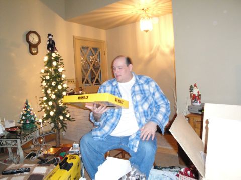 2000 Ford Crown Victoria - A man sits in a room with a Christmas tree, holding a DeWalt tool box.