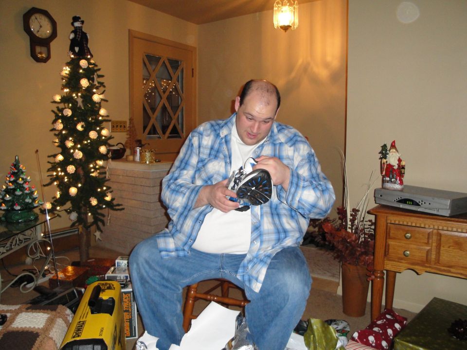 Man opening a gift in a decorated room with a Christmas tree