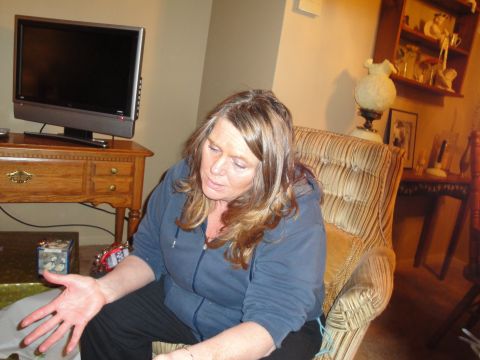 2000 Ford Crown Victoria - A woman sits in a patterned armchair in a living room, gesturing with her left hand.