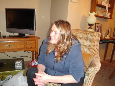 2000 Ford Crown Victoria - A woman is seated in a chair in a living room setting, with a television visible in the background.