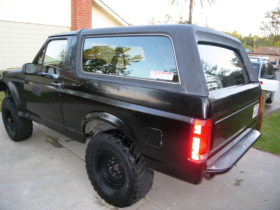 Black Ford Bronco with lifted suspension and large tires, viewed from the rear three-quarter angle