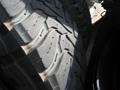 1986 Ford Bronco - The aggressive tread pattern of an off-road tire is shown in detail, with a second tire partially visible.