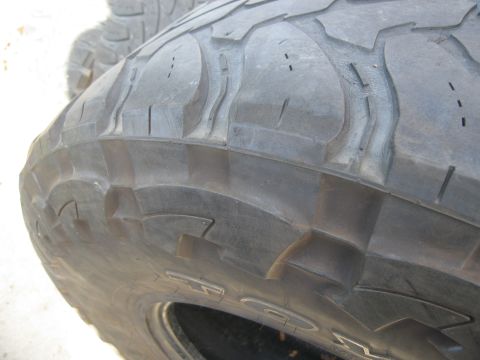 1986 Ford Bronco - A close-up view of a tire's tread pattern, with another tire visible in the background.