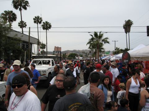 1986 Ford Bronco - A white off-road pickup truck is seen in a crowded street scene with palm trees and tents.
