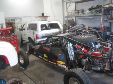 1986 Ford Bronco - A custom off-road buggy sits in a garage next to a white pickup truck, with various tools and parts visible.
