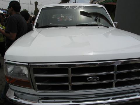 1986 Ford Bronco - A white Ford truck is shown from the front, with a chrome grille and a sticker on the windshield.