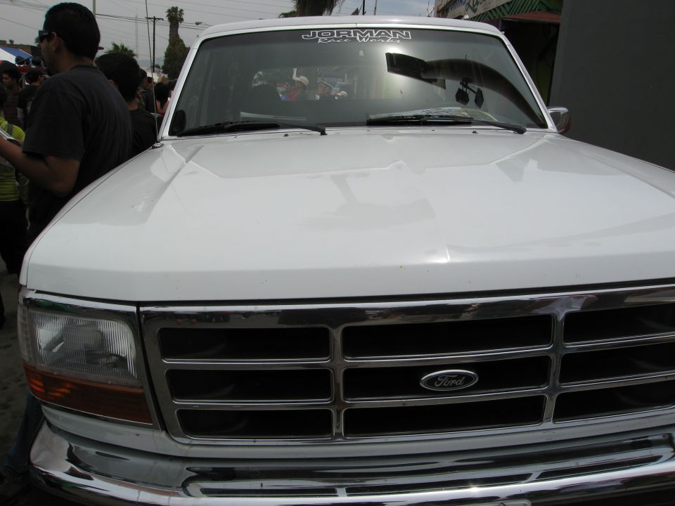 White Ford F-Series truck front grille and headlights, chrome bumper, with a sticker on the windshield