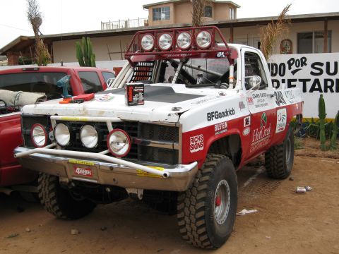 1986 Ford Bronco - This modified off-road truck features a prominent light bar and BFGoodrich tires, seen parked near another vehicle.