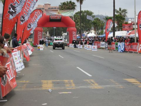 1986 Ford Bronco - An off-road SUV drives towards the finish line at the Baja 500 event in 2007, passing under a large inflatable arch.