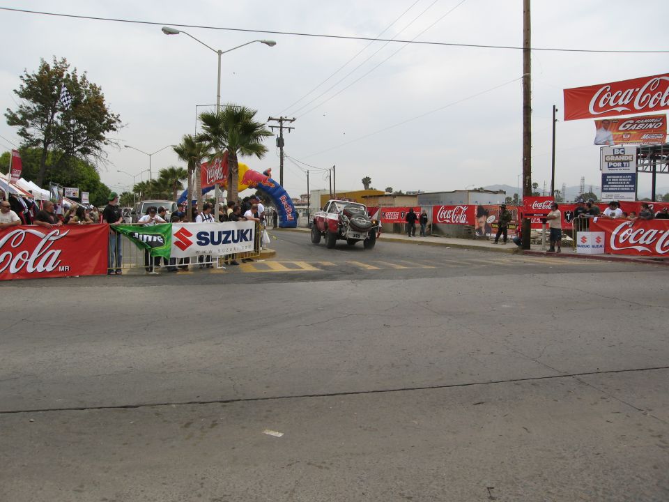 Race truck crossing an intersection with spectators and banners