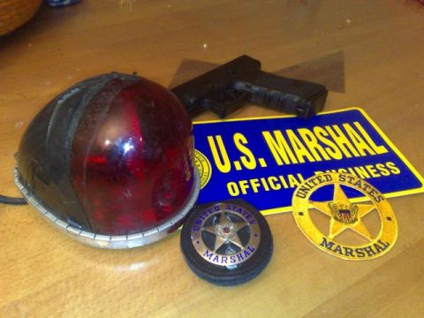 1991 Ford Crown Victoria - U.S. Marshal memorabilia including badges, a light, and a handgun are displayed on a wooden surface.