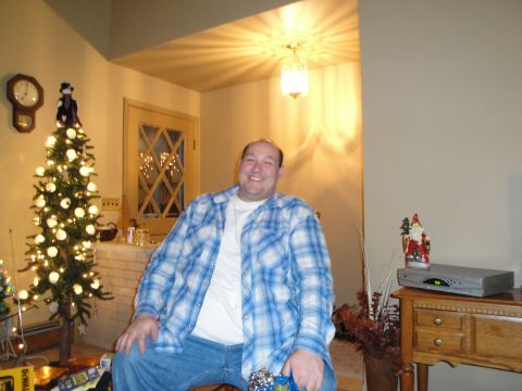 2000 Ford Crown Victoria - A man is seated in a room decorated for the holidays, with a Christmas tree and presents visible.
