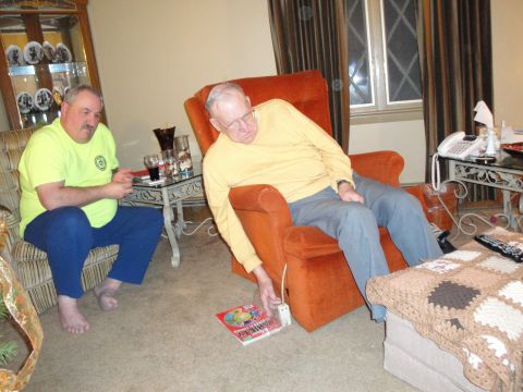2000 Ford Crown Victoria - Two men are in a living room, one seated in a recliner and the other on a sofa.