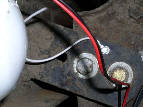 1979 Ford Bronco - Wiring and bolts are visible on a rusty metal bracket, with a partial white object on the left.