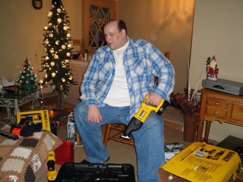 2000 Ford Crown Victoria - Man with new DeWalt reciprocating saw sits near a Christmas tree, surrounded by gifts.