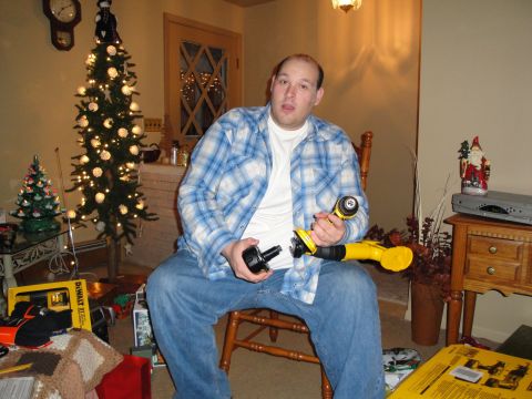 2000 Ford Crown Victoria - A man sits in a room decorated for Christmas, holding a power tool and its accessory.