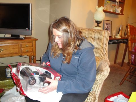 2000 Ford Crown Victoria - Woman opening a gift, which appears to be a toy, while sitting in a chair.