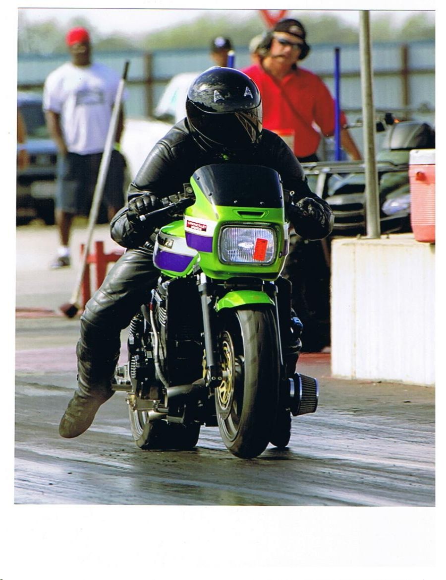 Green Kawasaki drag bike launching at the strip with rider in black leathers