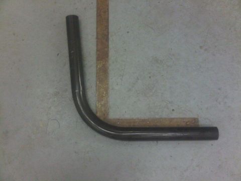 1996 Ford Bronco - A bent metal pipe lies on a concrete floor with some tape markings.