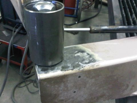 1996 Ford Bronco - A tool is positioned on a metal beam, possibly for repair or modification work.
