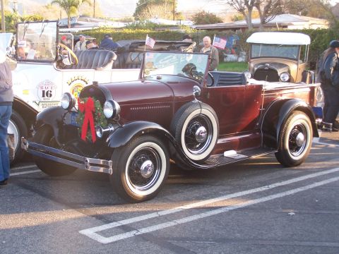 1990 Ford Bronco - Vintage maroon convertible pickup truck with a spare tire and holiday decorations.