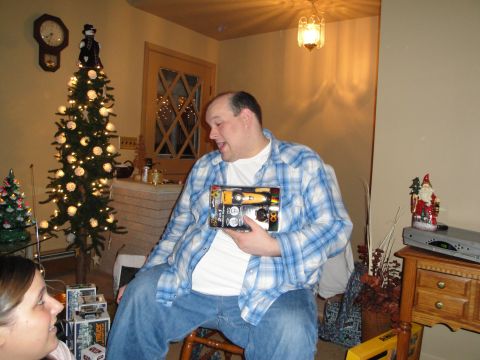 2000 Ford Crown Victoria - Man holding a toy car model kit during a holiday gathering.