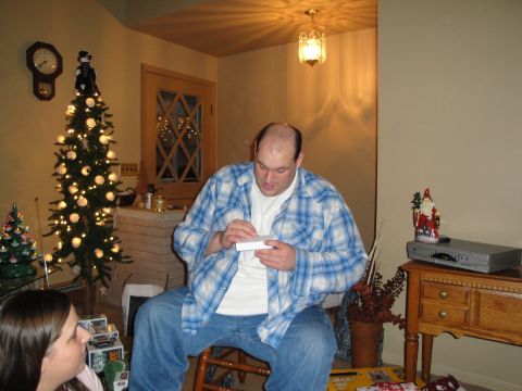 2000 Ford Crown Victoria - A man opens a gift while sitting on a stool in a room decorated for Christmas.