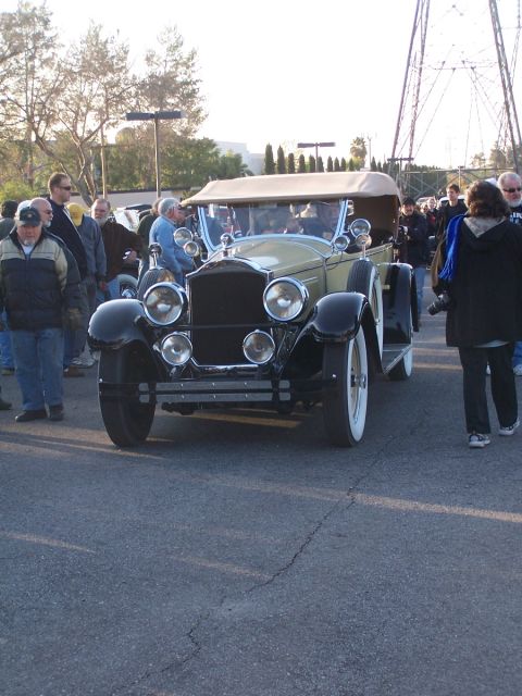 1990 Ford Bronco - A vintage tan convertible with distinctive black fenders and white wall tires is displayed outdoors among onlookers.