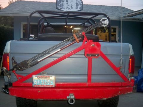 1985 Ford Bronco - Rear view of a 1985 Ford Bronco, equipped with a red spare tire carrier and a Hi-Lift jack mounted on the back.