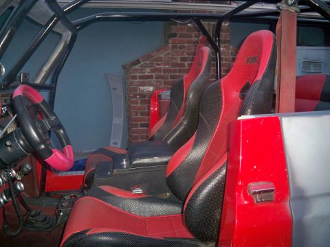 1985 Ford Bronco - The interior features racing-style seats and a prominent roll cage structure.
